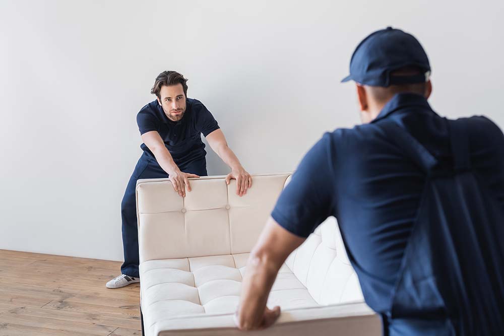 workmen moving white sofa together with colleague on blurred for Furniture, Fixtures & Equipment delivery